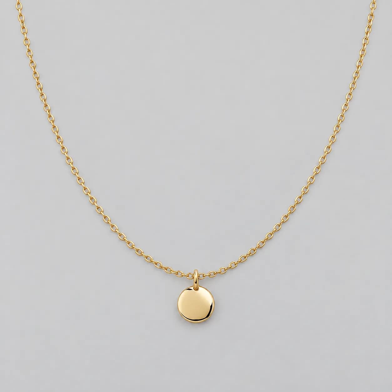 Foto fuente de un collar dorado ficticio con dije redondo pequeno sobre fondo liso