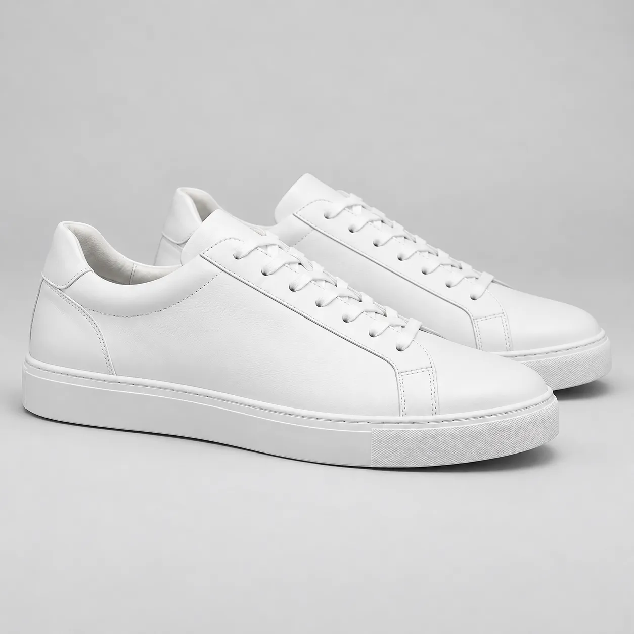 Pair of white leather low-top sneakers in a premium studio shot on a neutral background